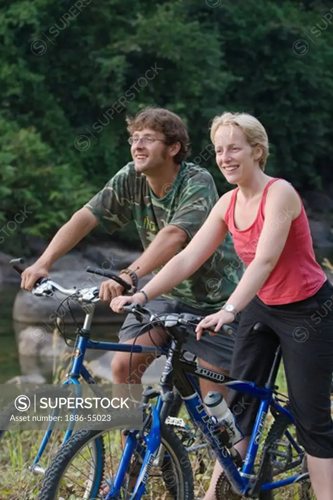 A traveling couple enjoy a mountain bike ride near the Thai village of Kuraburi located near the North Andaman Sea - THAILAND