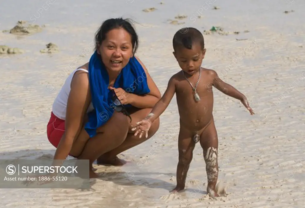 Moken (sea gypsy) child plays with a friend at the permanent settlement on Ko Surin Thai Island in Mu Ko Surin National Park -  ANDAMAN SEA, THAILAND