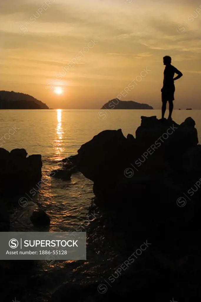 A traveler enjoys a tropical sunset from Ko Surin Nuea Island in Mu Ko Surin National Park -  ANDAMAN SEA, THAILAND