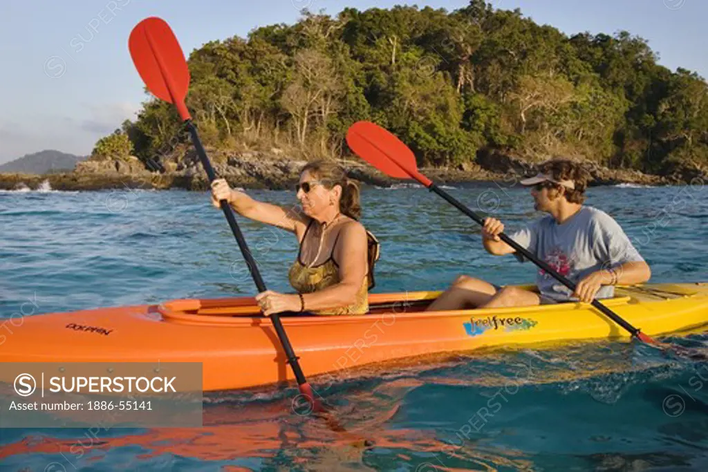 Travelers enjoy an early morning kayak paddle in the North Andaman Sea along the coast of Ko Surin Nuea Island in Mu Ko Surin National Park, THAILAND