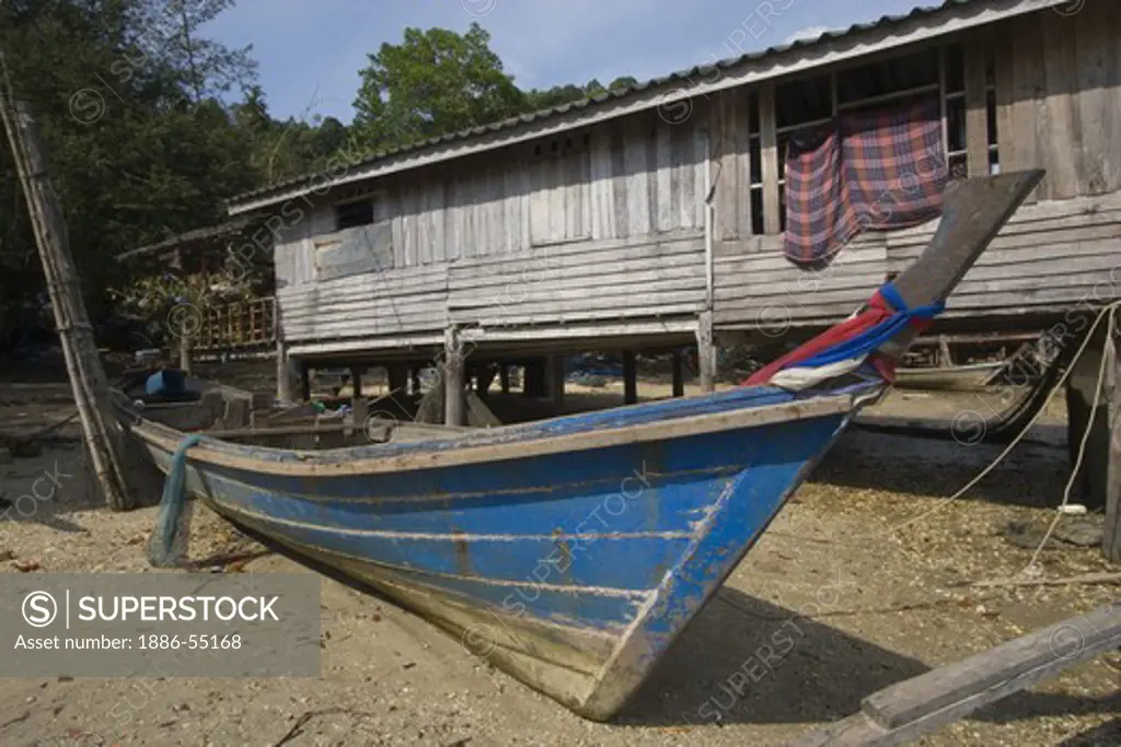 Fishing boat and house in the remote village of Laem Naew, a fishing village on the North Andaman Sea - THAILAND