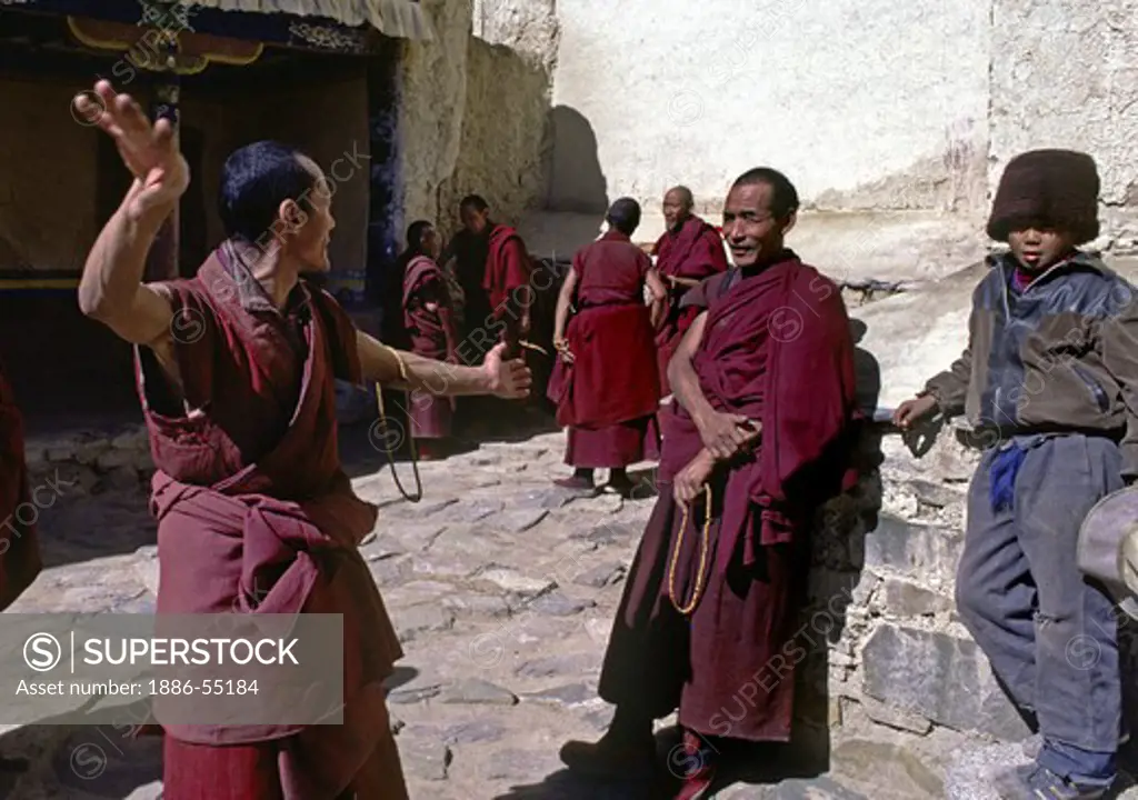 Monks practicing ritualized TIBETAN BUDDHIST debate at TASHILHUNPO MONASTERY - SHIGATSE, TIBET