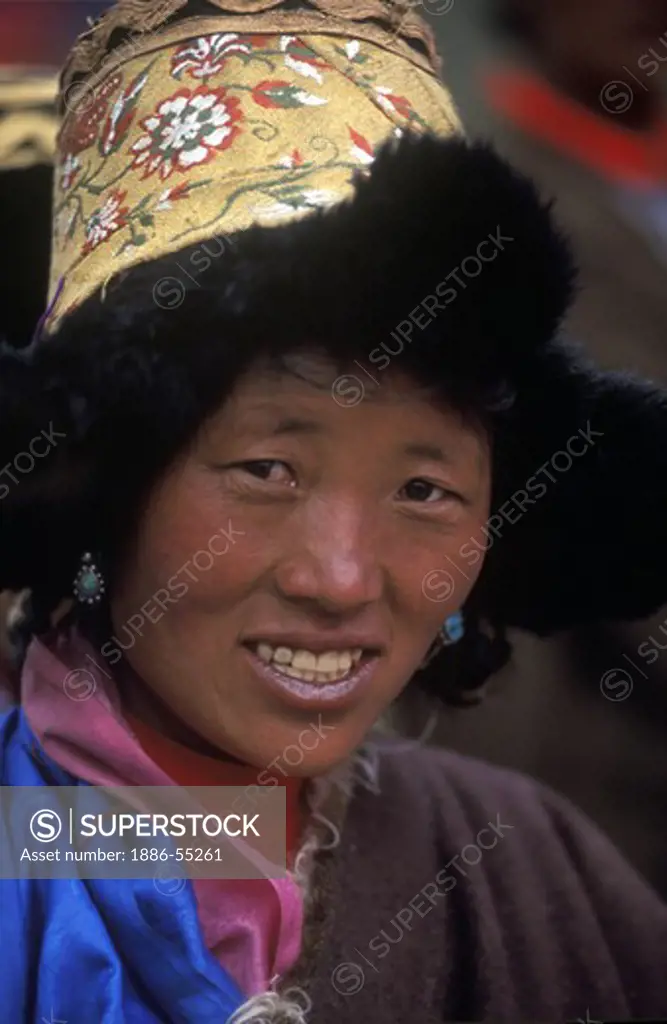TIBETAN WOMAN with traditional FUR LINED HAT & TURQUOISE EARRINGS at a festival near KYAKYARU near SAGA, TIBET