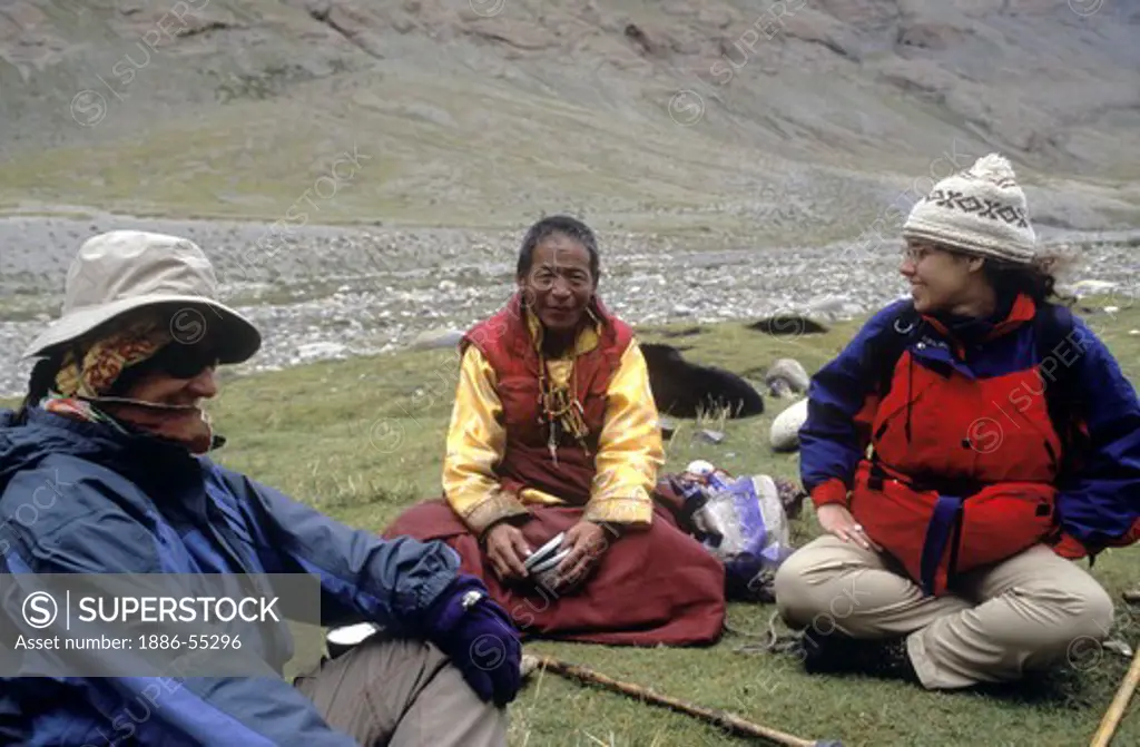 BUDDHIST MONK and travelers rest while hiking around MOUNT KAILASH (6638 M) the most sacred HIMALAYAN PEAK - TIBET