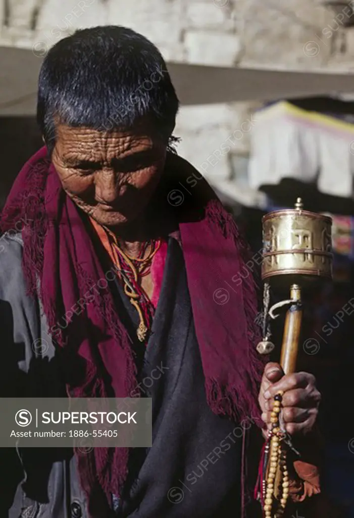 A Tibetan nun on pilgrimage spins her prayer wheel while circumnambulating the Barkhor - Lhasa, Tibet