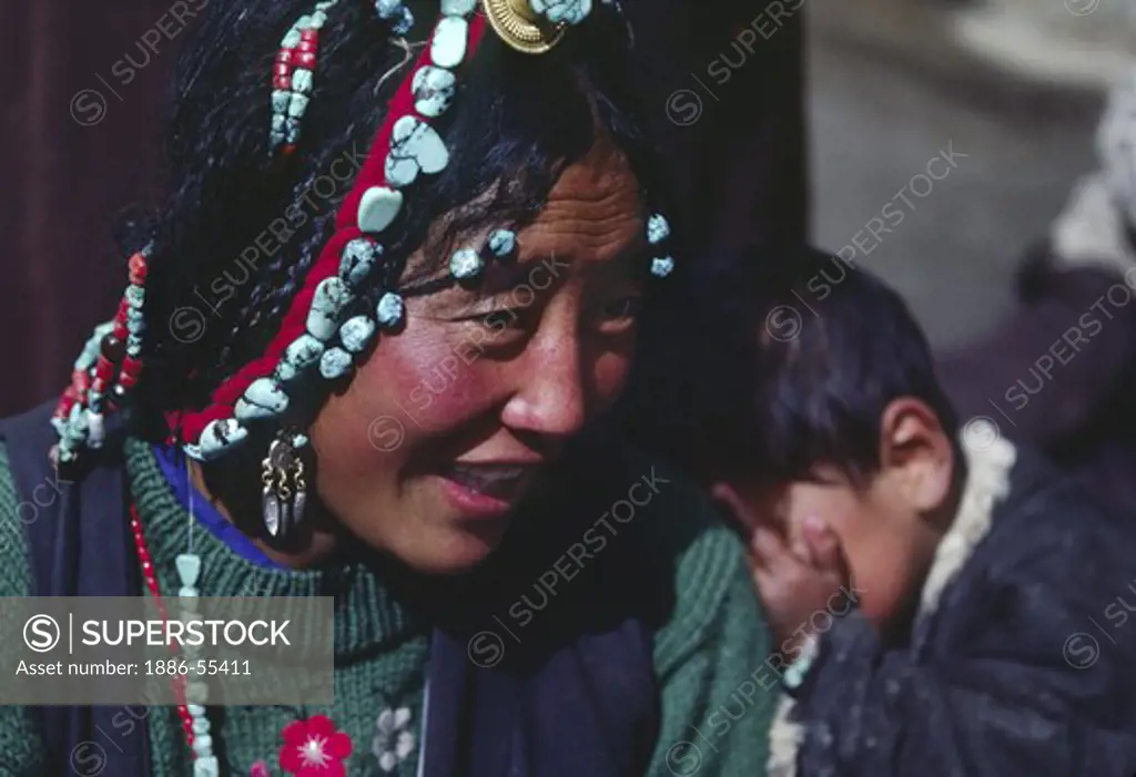 Tibetan beauty with elaborate tourquoise headdress and her son on the Barkhor -Lhasa, Tibet