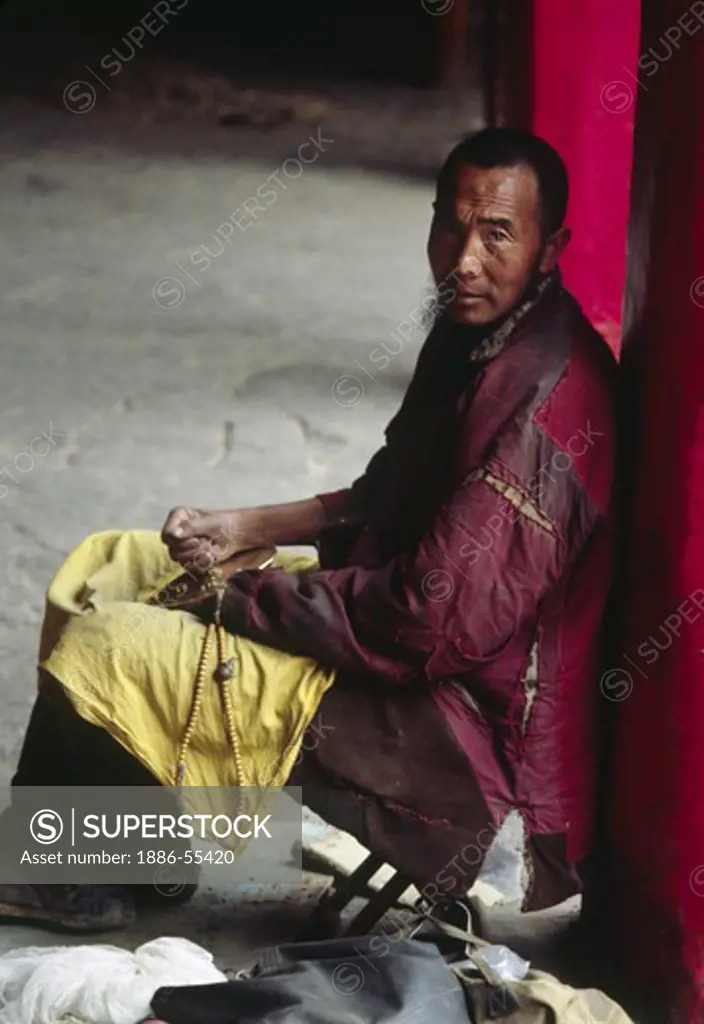 Pilgrim with mala does puja in from of the  Jokhang Temple - Lhasa, Tibet