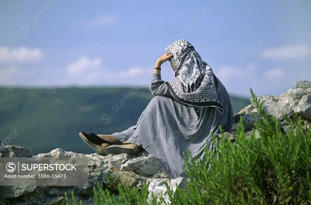 Muslim woman sits on a castle wall overlooking the BOSPHORUS - Turkey