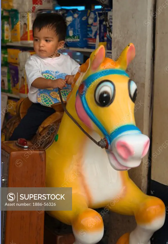 A young MEXICAN BOY on a coin operated ROCKING HORSE  - GUANAJUATO,  MEXICO
