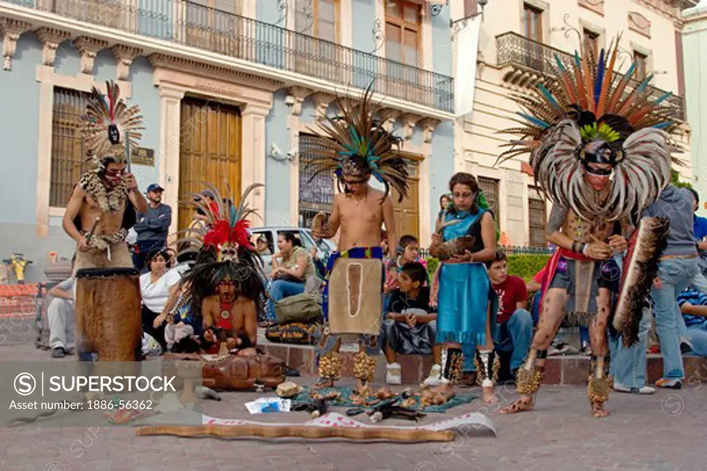 An AZTEC DANCE TROUPE performs in traditional warrior feathered COSTUMES  during the CERVANTINO FESTIVAL  - GUANAJUATO, MEXICO