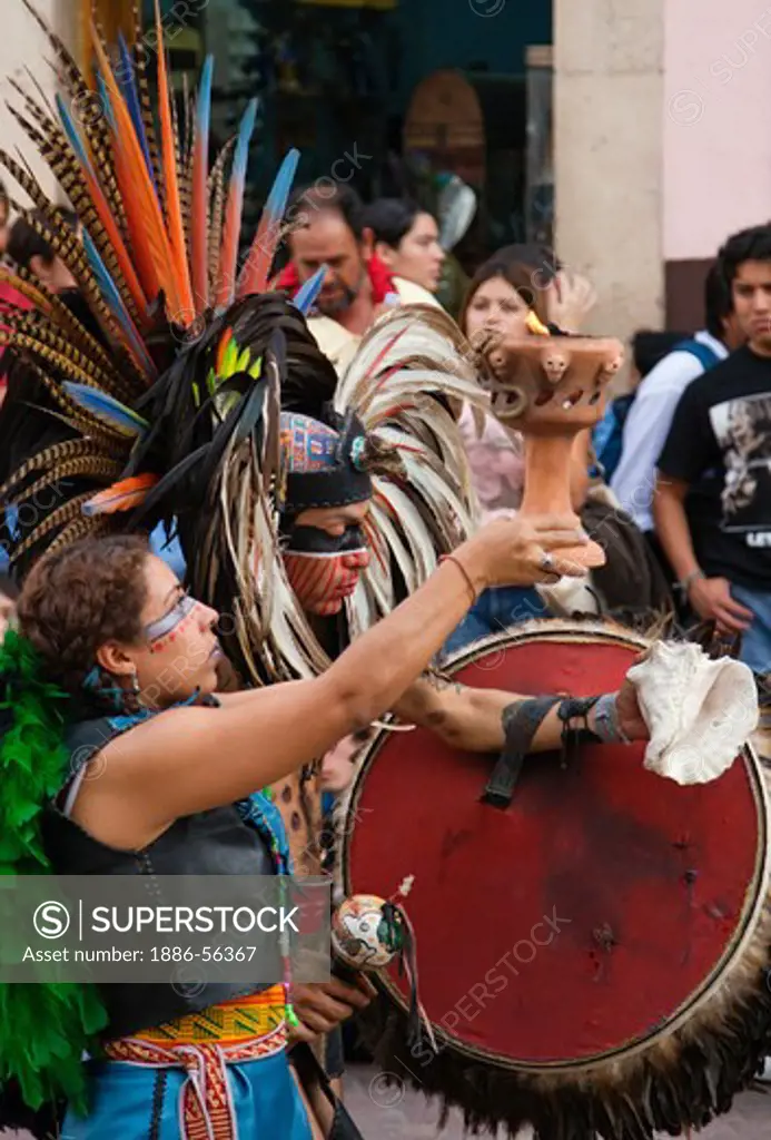 An AZTEC DANCE TROUPE performs with burnt offerings and CONCH in traditional feathered COSTUMES  during the CERVANTINO FESTIVAL - GUANAJUATO, MEXICO