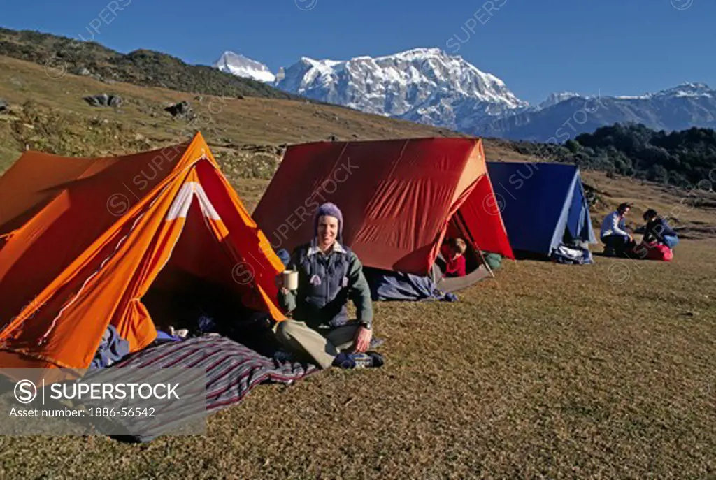 Trekkers enjoy tent tea while camping above Siklis village with Lamjung Himal in the background - NEPAL HIMALAYA