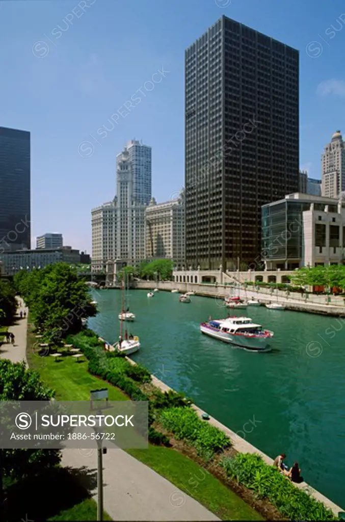 BOATS head down the CHICAGO RIVER on route to Lake Michigan backdropped by the city - CHICAGO, ILLINOIS