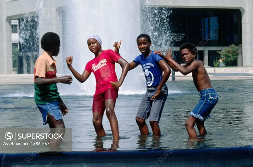 Black kids play in a fountain during the summer heat - MEMPHIS, TENNESSEE