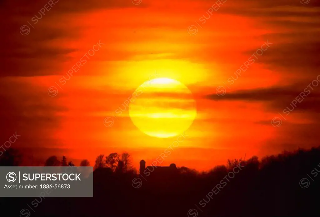 Sunset with sun and barn silhouette, Pennsylvania.