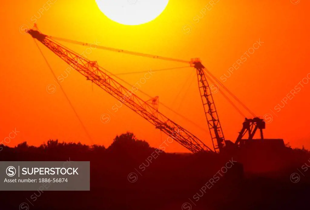 Sunset silhouette of giant dragline at Texas coal strip mine.