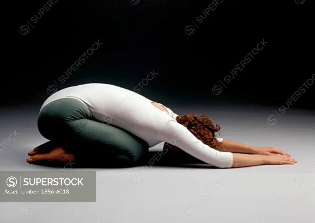 A female YOGINI doing the POSE OF THE CHILD 