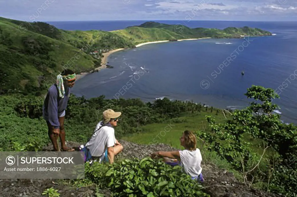 Visitors enjoy the view of a FIJIAN VILLAGE on WAYA ISLAND after a long uphill hike - YASAWA ISLAND GROUP, FIJI