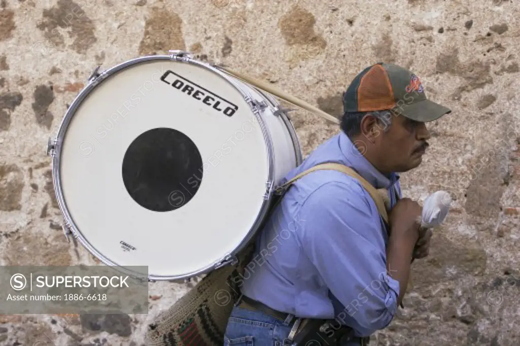 Musician carrying base drum to a bull fight in the Plaza de Torres SAN MIGUEL DE ALLENDE, MEXICO    