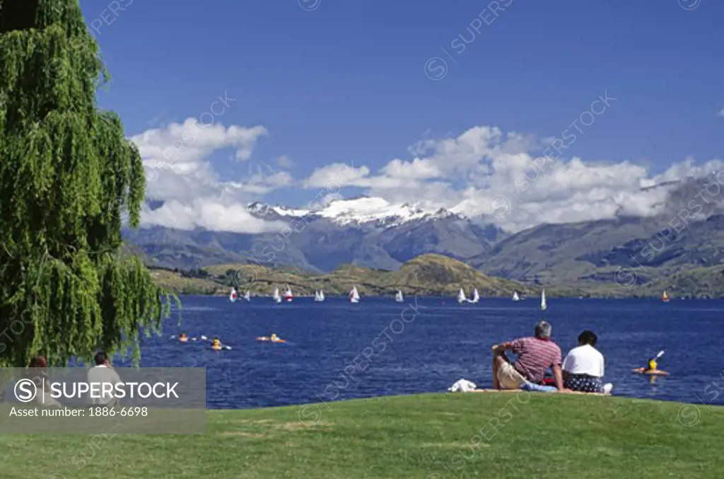 Picnickers watch the sailboats & kakyaks on LAKE WANAKA on a beautiful summer afternoon - SOUTH ISLAND, NEW ZEALAND
