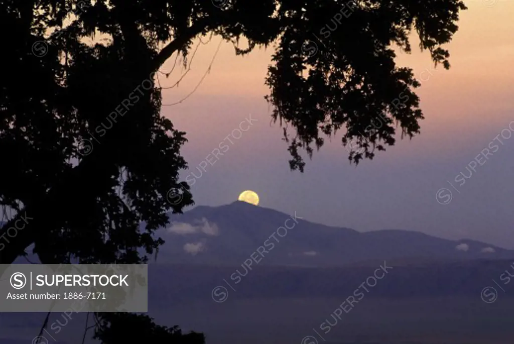 The FULL MOON sets as dawn breaks over NGORONGORO CRATER CONSERVATION AREA, TANZANIA