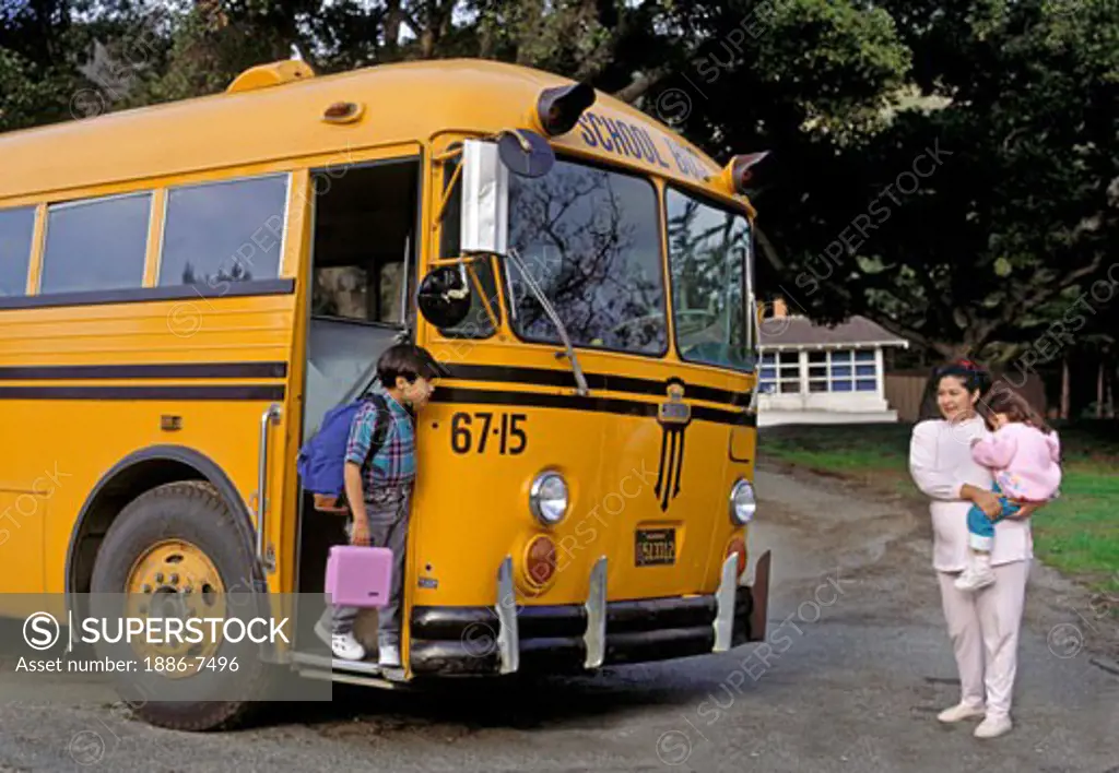 HISPANIC WOMAN meeting her SON at the SCHOOL BUS with her young daughter on her hip 
