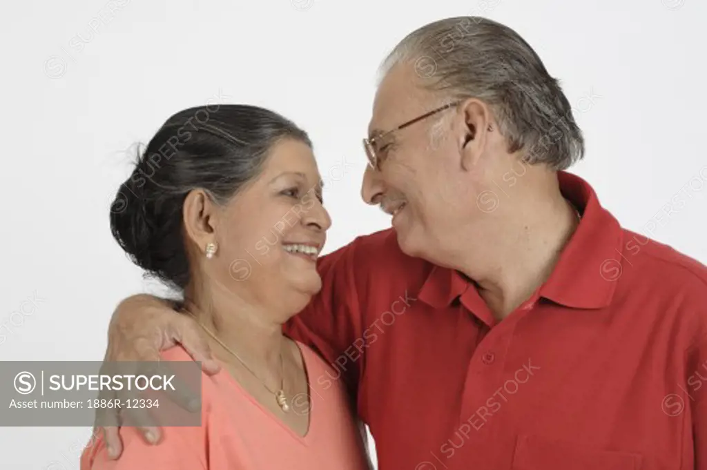 Old couple, old man wearing red T Shirt, Specs, Spectacles, glasses, old lady wearing light tomato colour top, gold chain with pendent, earrings, old man holding old woman around her shoulder, looking at her, both smiling, MR # 703B and 703A