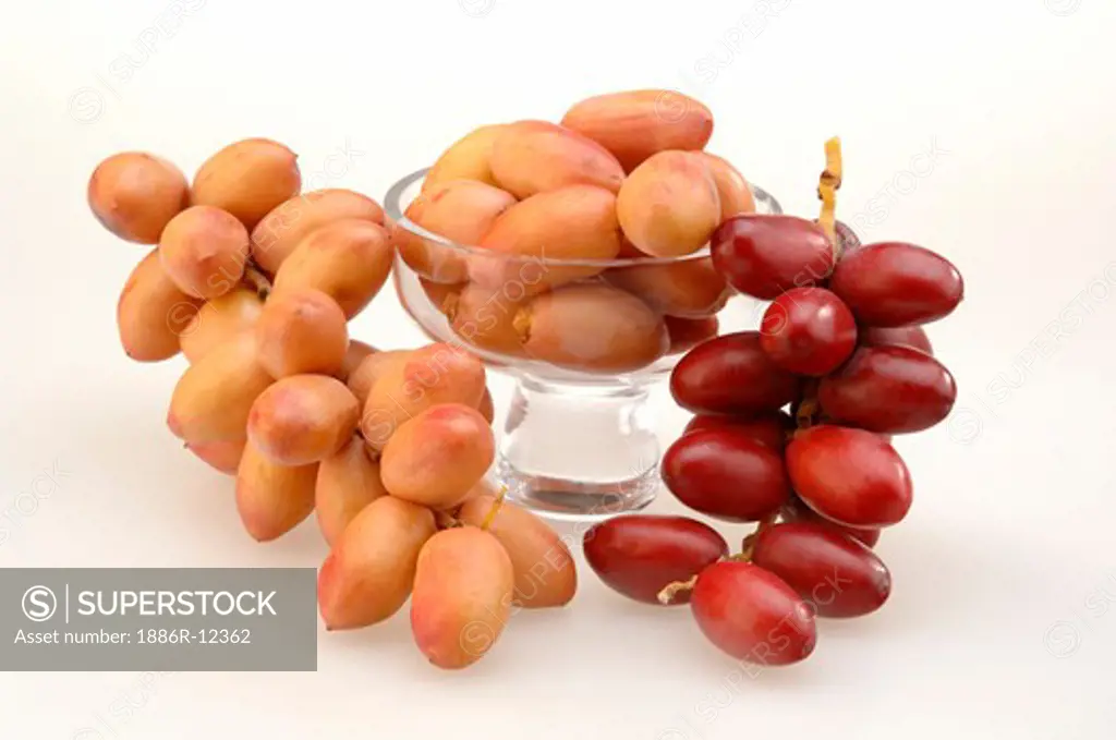 Fruit, two red and pink dates bunch kept in cup with white background