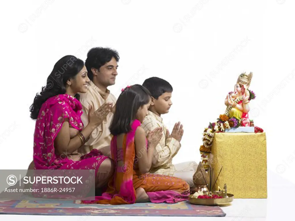 VDA200242 : South Asian Indian family with father, mother, son and daughter sitting praying to lord Ganesha wearing traditional dress kurta, pajama, pink and orange color dress, pink dress, MR # 698, 699, 700, 701