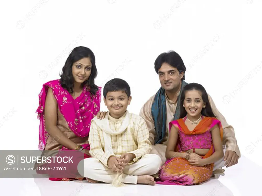 VDA200249 : South Asian Indian family with father, mother, son and daughter sitting smiling and looking at camera wearing traditional dress kurta, pajama, pink and orange color dress, pink dress, MR # 698, 699, 700, 701