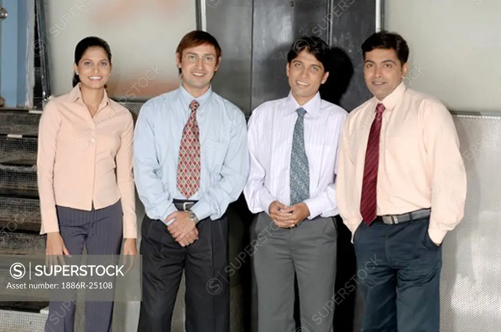 MAK200706 : South Asian Indian businessmen and woman standing,  smiling and looking at each other wearing blue shirt,  black pant,  pink shirt,  white shirt and tie in Office MR #  670E,  670F, 670G,  670H