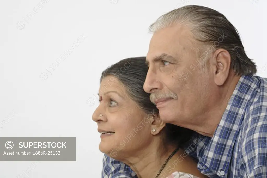 Old happy couple, old man wearing blue and white checkes shirt, old lady wearing Saree, Mangalsutra, Nose ring or stud, Saree pin, earrings, kumkum faces in profile, very close to each other and smiling, MR # 703A and 703B