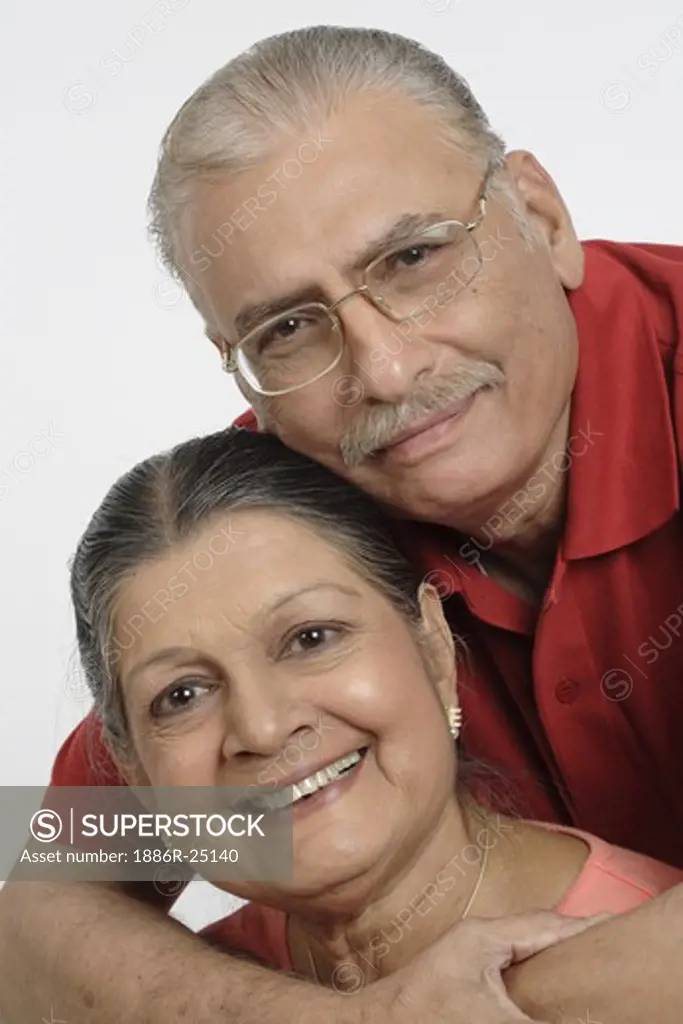 Old couple, old man wearing red T Shirt, Specs, Spectacles, glasses, old lady wearing light tomato colour top, gold chain with pendent, earrings old man holding old woman close to him putting his both the arms around her neck, both happy, smiling, MR # 703B and 703A