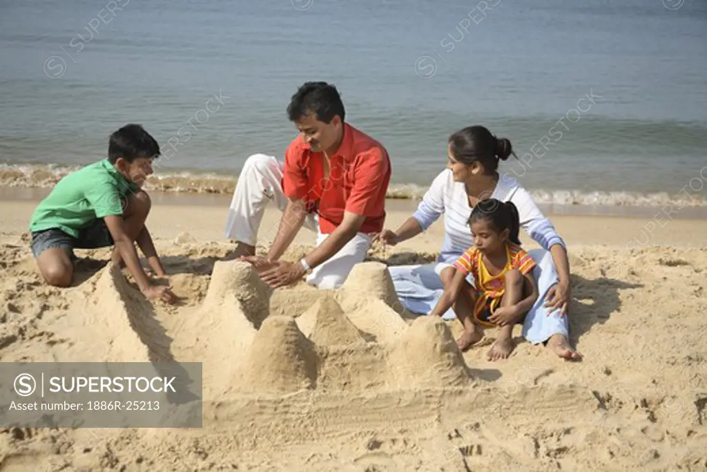 South Asian Indian parent and children making sand castle on seashore at Shiroda; Dist. Sindhudurga; Maharashtra; India MR#703D;703E;703F;703G