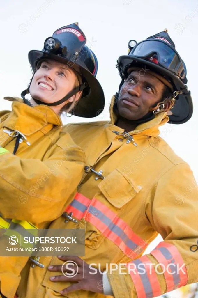 Two firefighters standing outdoors wearing helmets