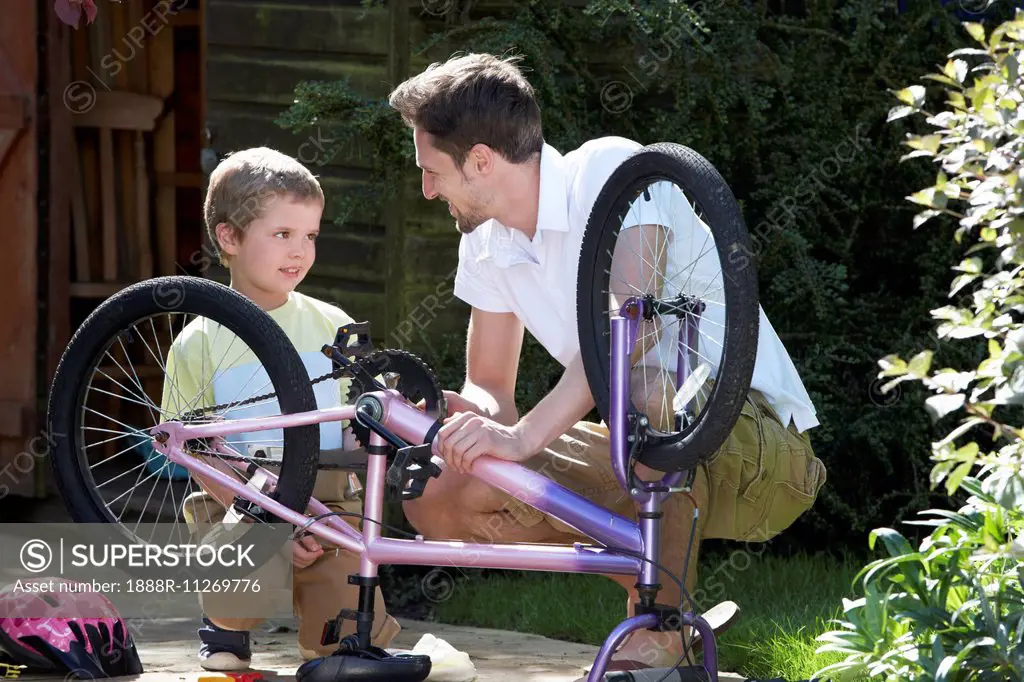 Father And Son Mending Bike Together