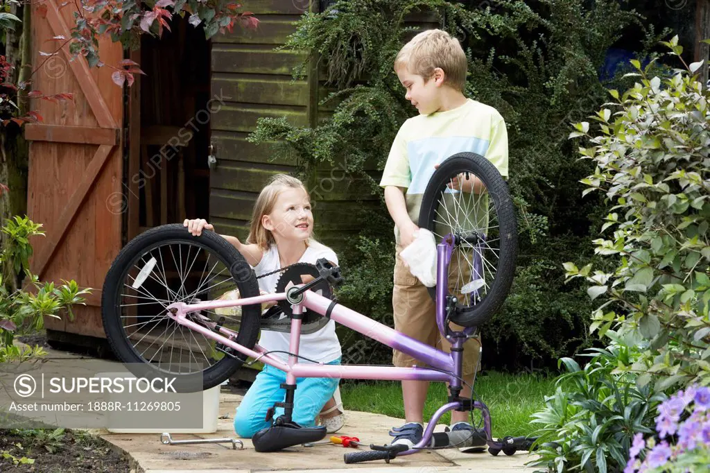 Two Children Cleaning Bike Together