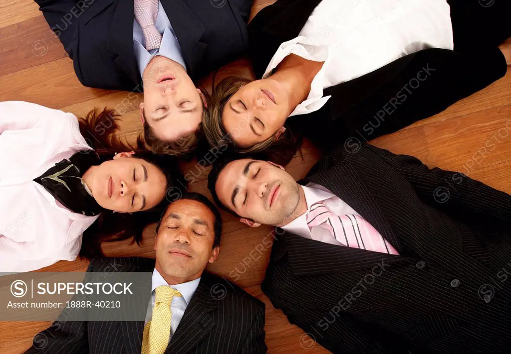 business dream team _ all young and successful businessmen and businesswomen relaxing on the floor with their heads together