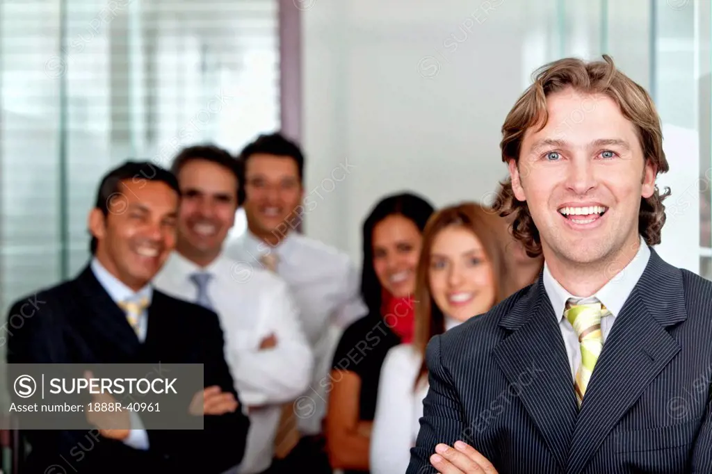 Business man smiling at the office with a group behind