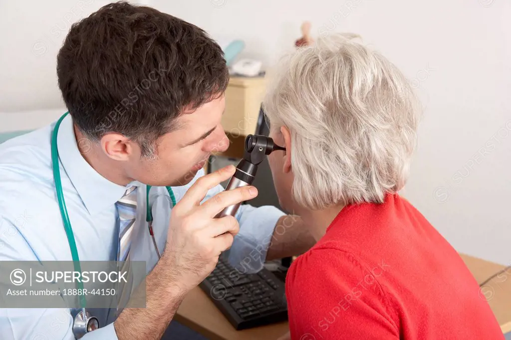 British doctor examining senior woman´s ear