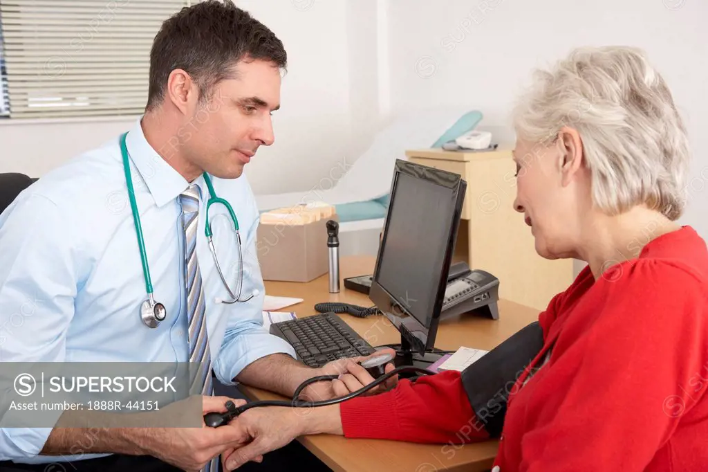 British doctor taking senior woman´s blood pressure
