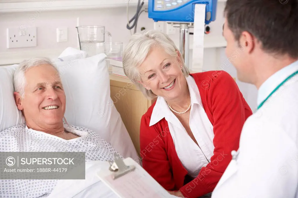 Doctor talking to senior couple on USA Hospital ward