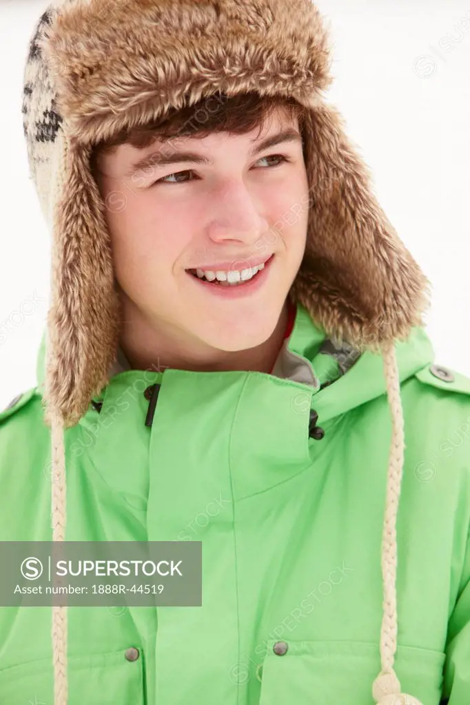 Portrait Of Teenage Boy In Snow Wearing Fur Hat
