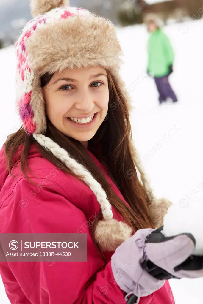 Teenage Couple Having Snowball Fight Wearing Fur Hats