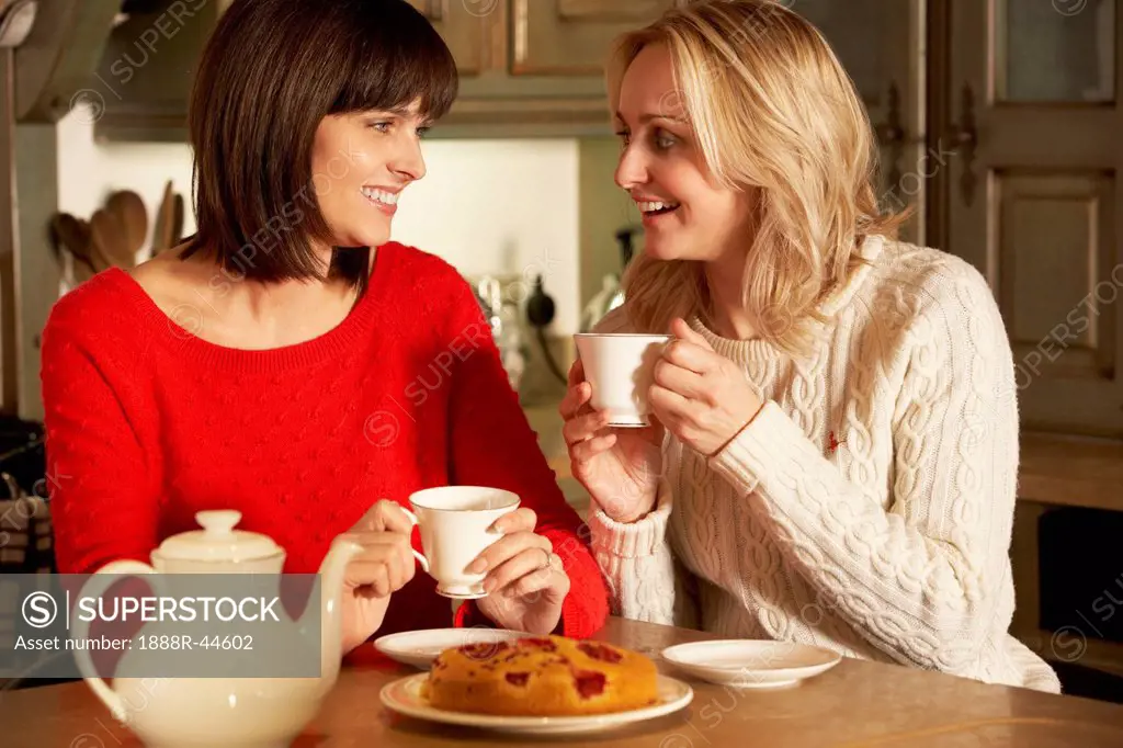 Two Middle Aged Women Enjoying Tea And Cake Together