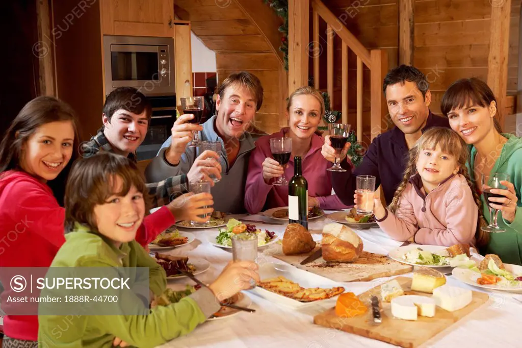 Two Familes Enjoying Meal In Alpine Chalet Together