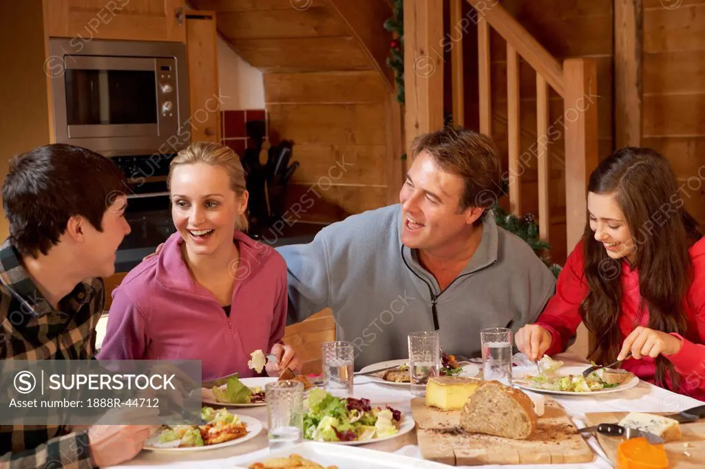 Teenage Family Enjoying Meal In Alpine Chalet Together
