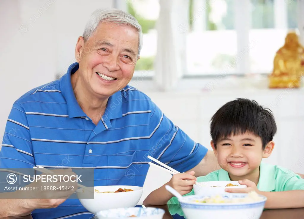 Portrait Of Chinese Grandfather And Grandson Eating Meal Together