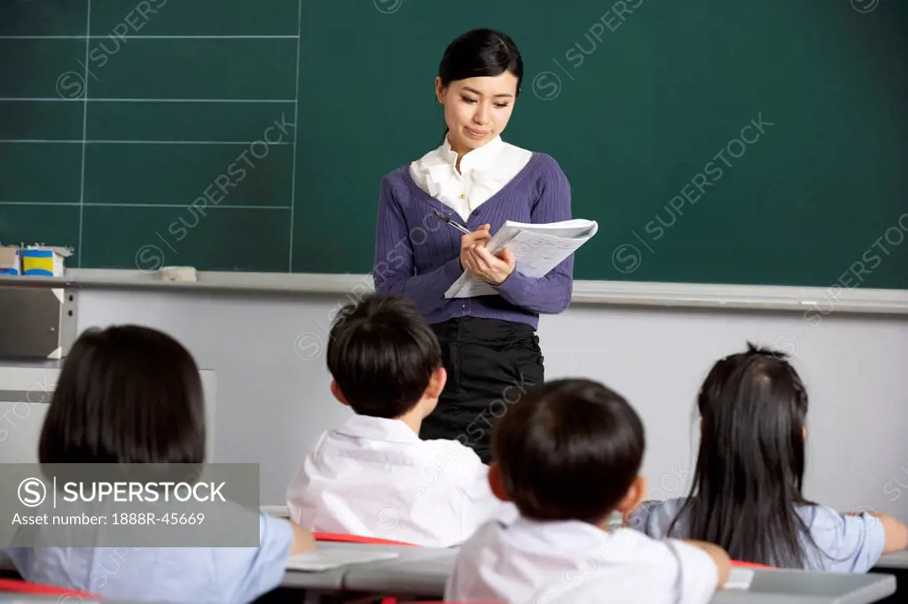 Teacher With Students In Chinese School Classroom