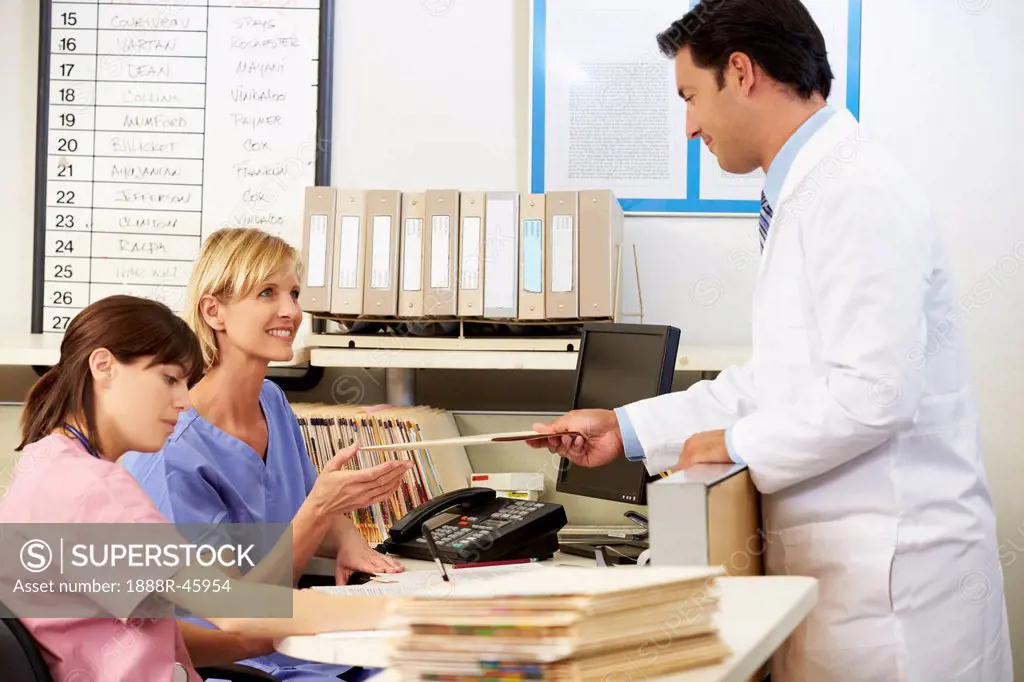 Doctor With Two Nurses Working At Nurses Station